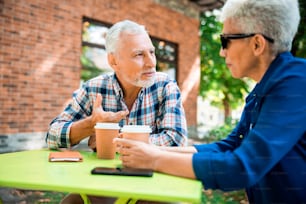 Senior couple sitting at the table with coffee and chatting stock photo