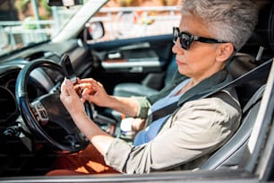 Mulher idosa que verifica mensagens no smartphone no auto stock photo