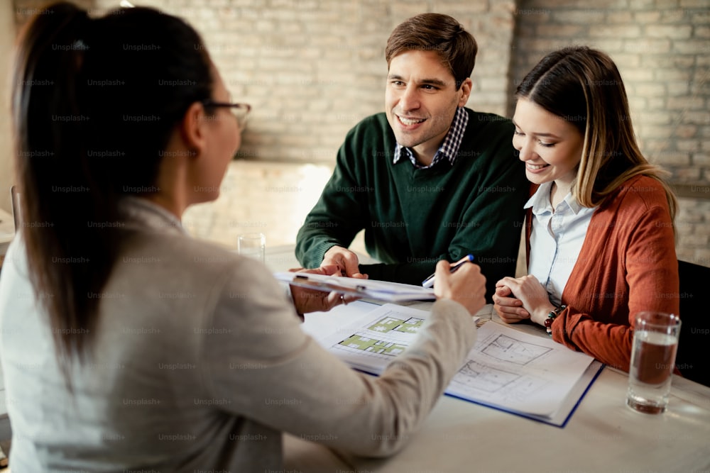 Happy couple having a meeting with real estate agent and communicating about terms of an lease agreement.