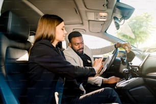 Autogeschäft, Autoverkauf, Navigation und Menschenkonzept - Nahaufnahme eines multiethnischen Paares, das mit Tablet-Computer im Auto sitzt und auf den Bildschirm schaut.