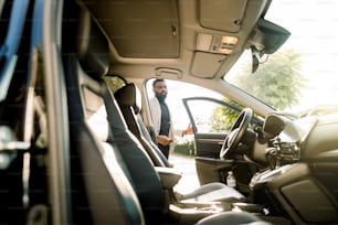 Busy African young man in suit getting in car. Happy young businessman getting inside his car. African man in suit stepping in his vehicle