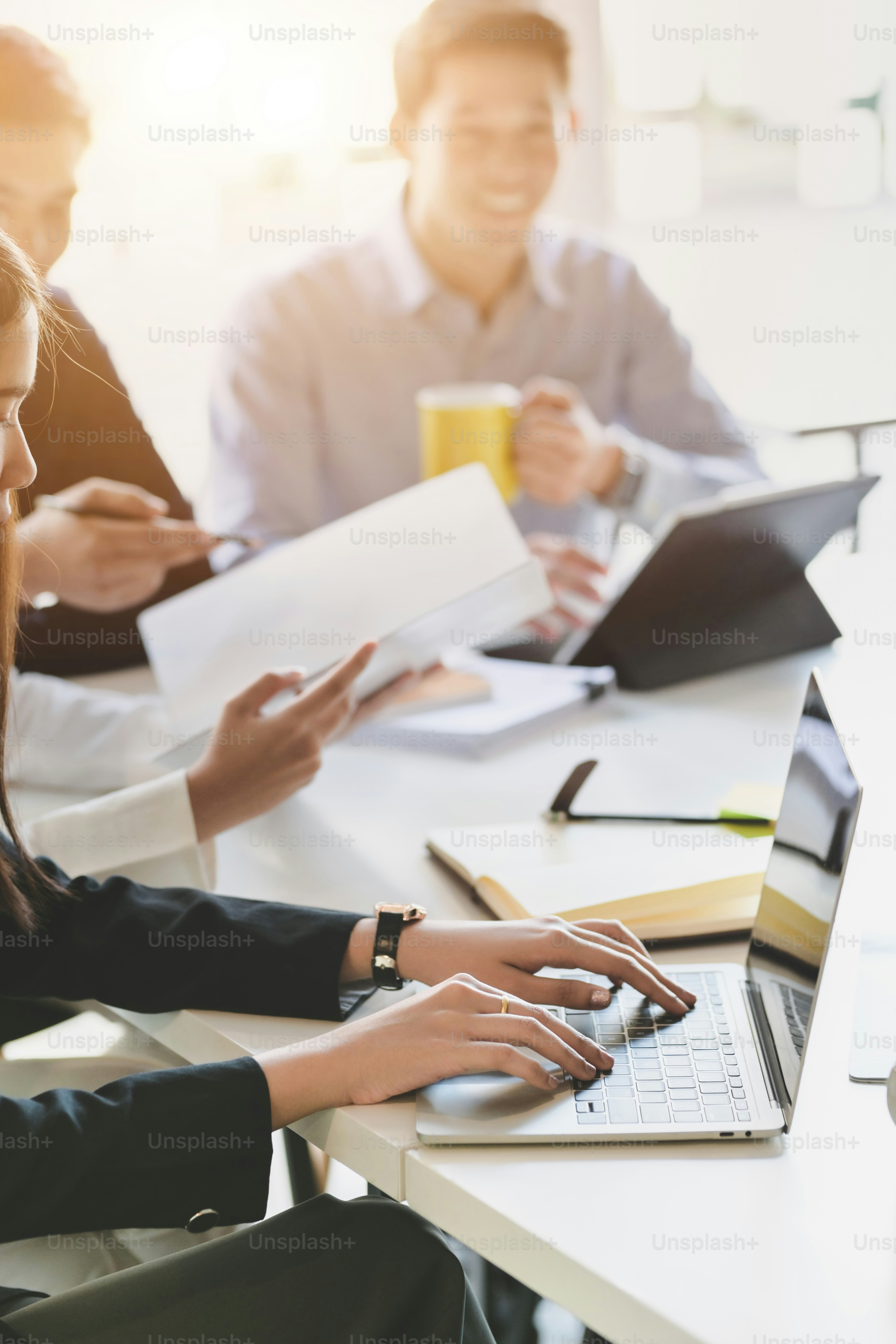 Cropped shot of young female business focusing on her project while siting in meeting room with co worker and office supplies