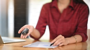 Close-up Young woman together with the car purchase agreement and keys.