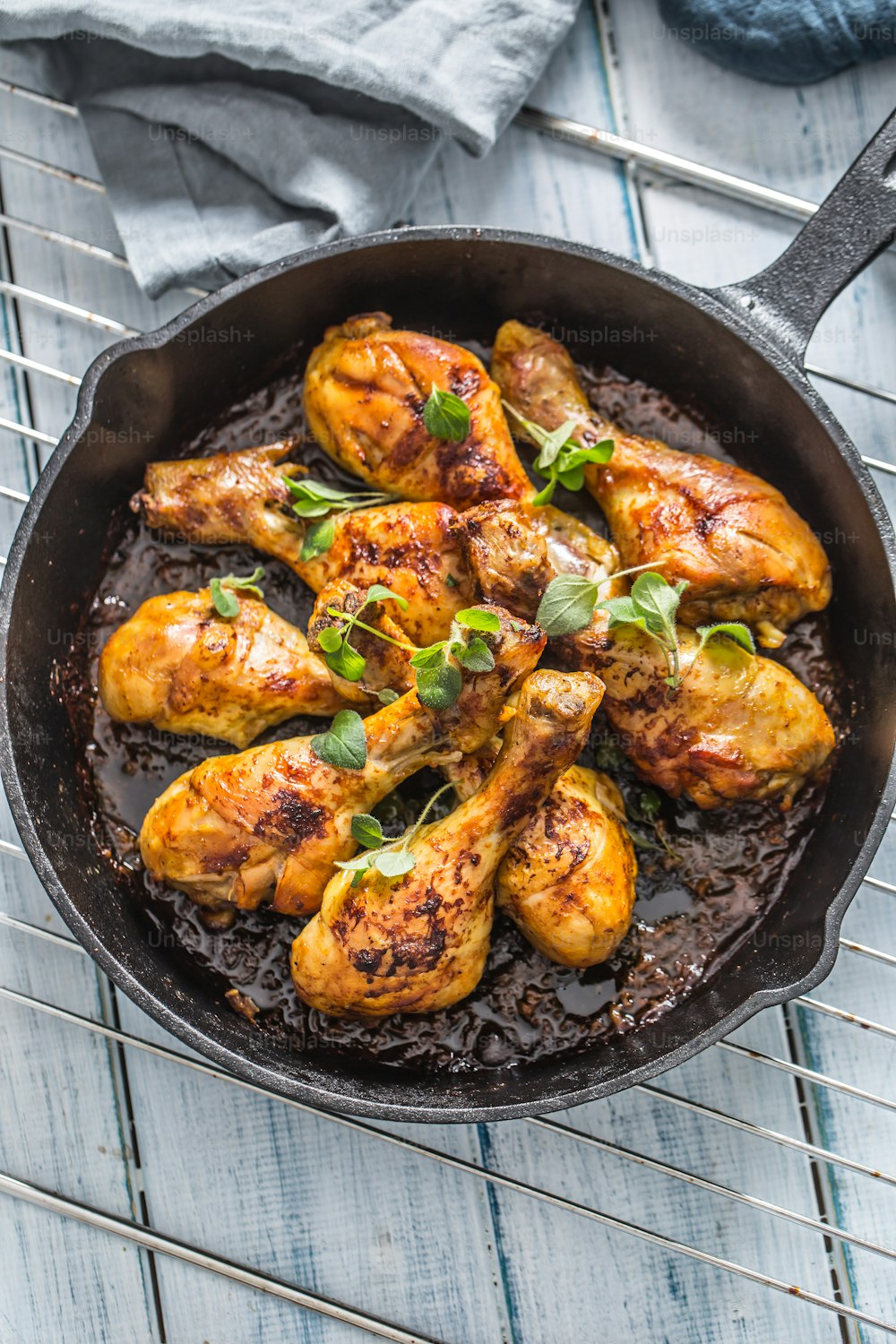 Roasted chicken legs in pan with herbs - close up.