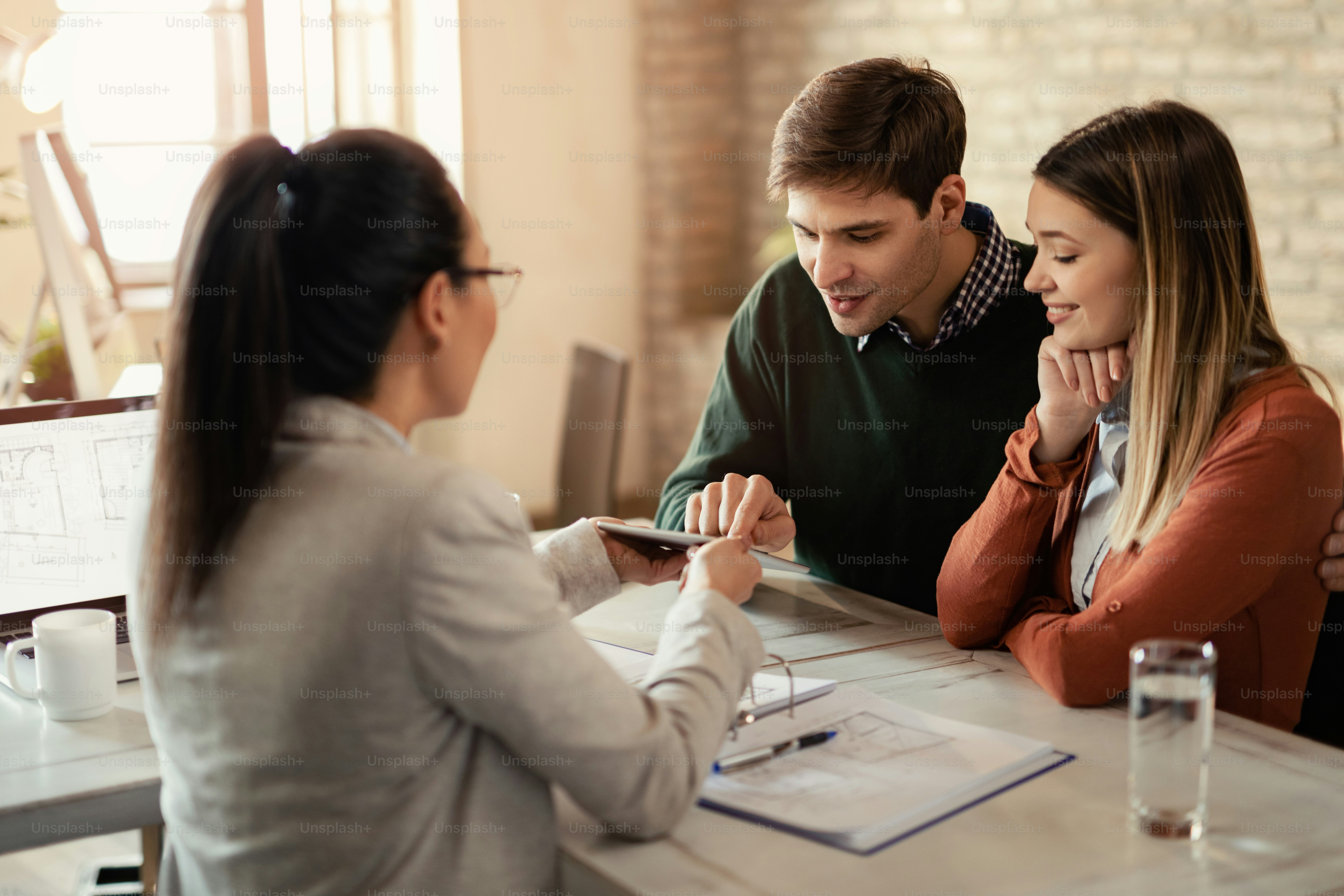 Young couple and their insurance agent using digital tablet during a meeting in the office.