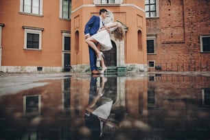 Stilvolles Paar, das in der europäischen Stadtstraße auf dem Hintergrund alter Architektur und Reflexion im Wasser tanzt. Modischer Mann und verliebte Frau tanzen. Gemeinsam unterwegs in Europa