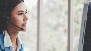 Customer support agent or call center with headset works on desktop computer while supporting the customer on phone call. Operator service business representative concept.