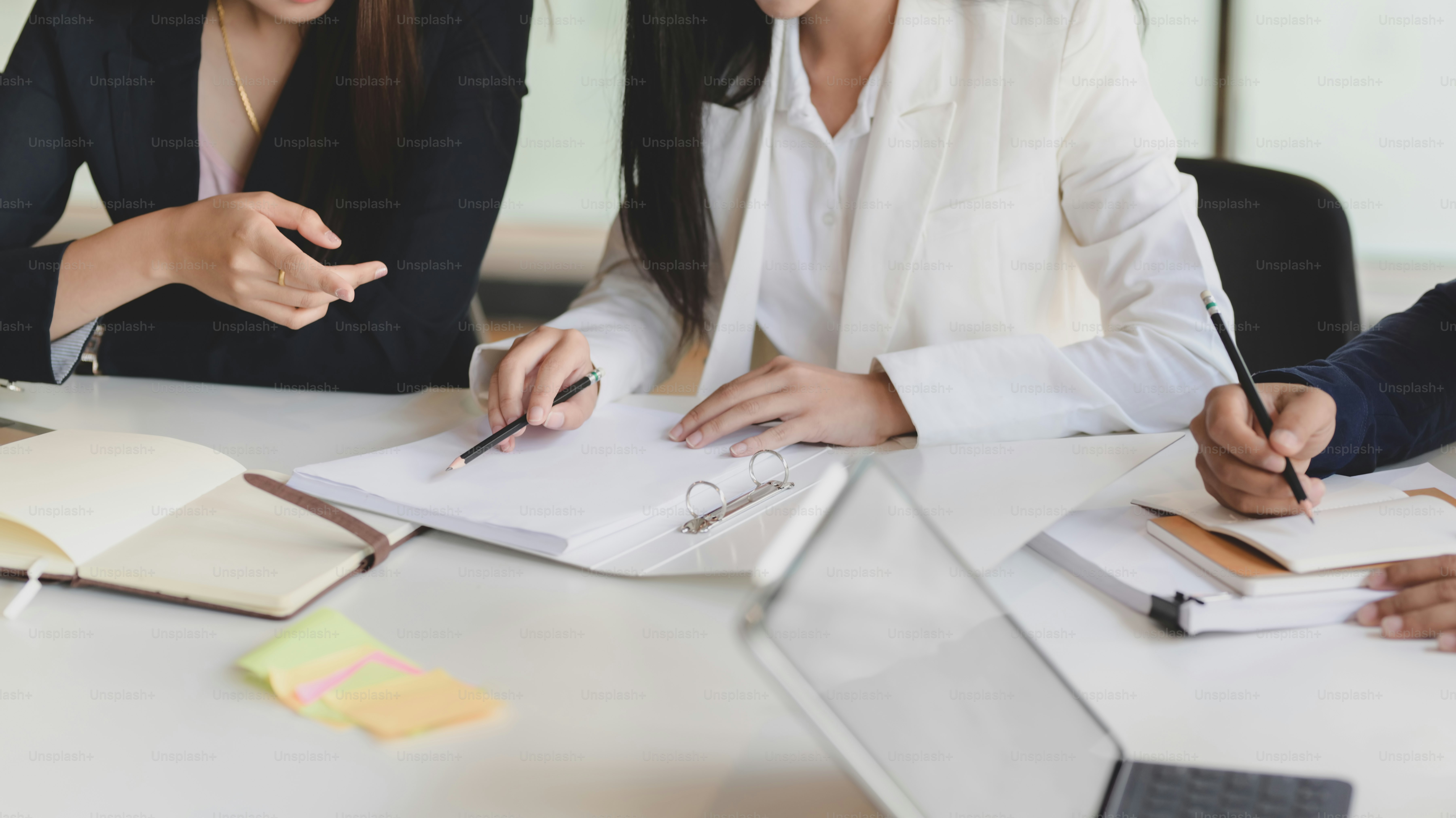 Cropped shot of two of businesswoman discussing on their project while sitting in simple co working space with office supplies