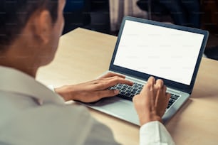 Persona de negocios o trabajador de oficina que usa una computadora portátil mientras está sentado en el escritorio.