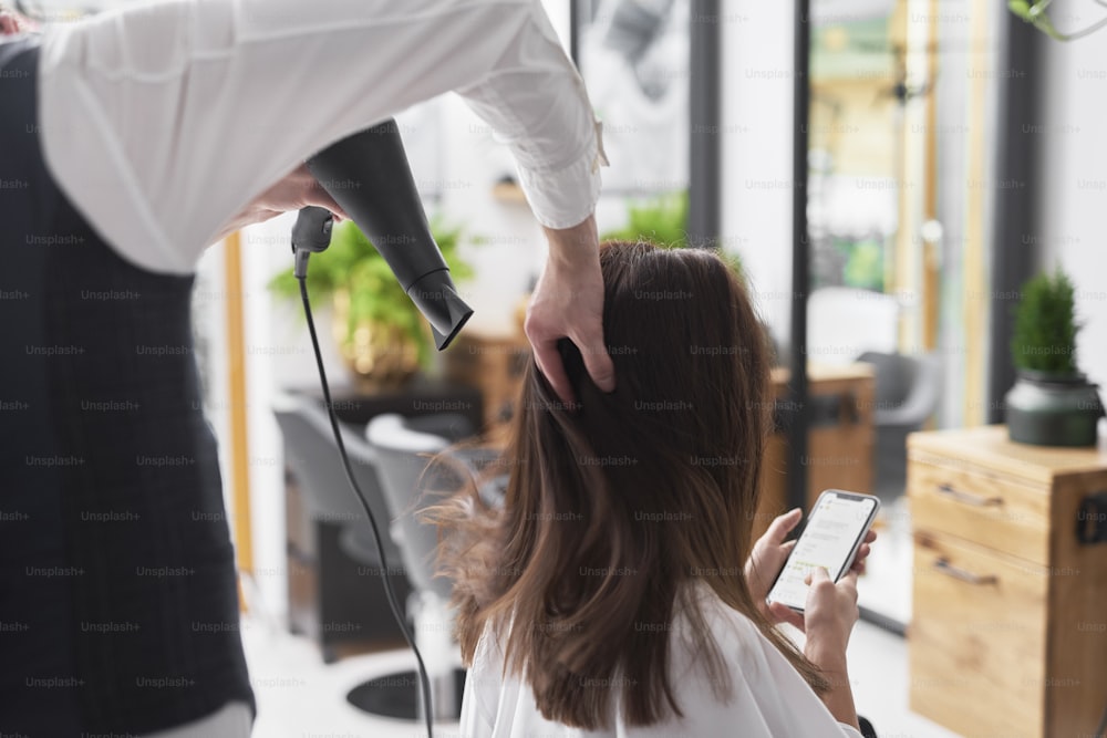 Close up of hairdresser using hair dryer