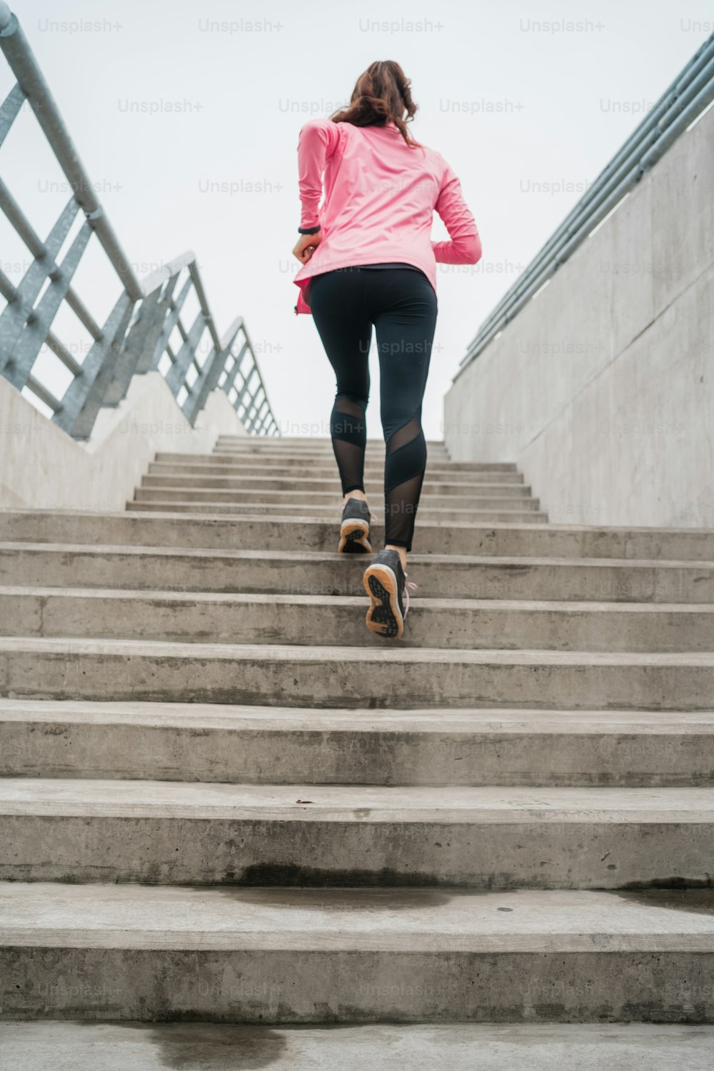 Ritratto di una donna sportiva che corre sulle scale all'aperto. Concetti di fitness, sport e stile di vita sano.