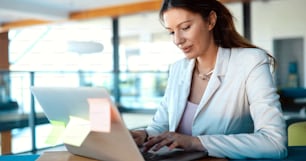 Attractive young female architect working on laptop in office