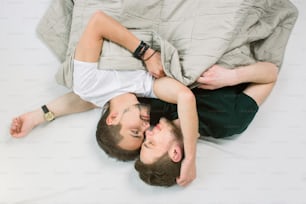 Joven pareja gay acostada en la cama, vista superior. Día de San Valentín. Dos chicos sexys en la cama.
