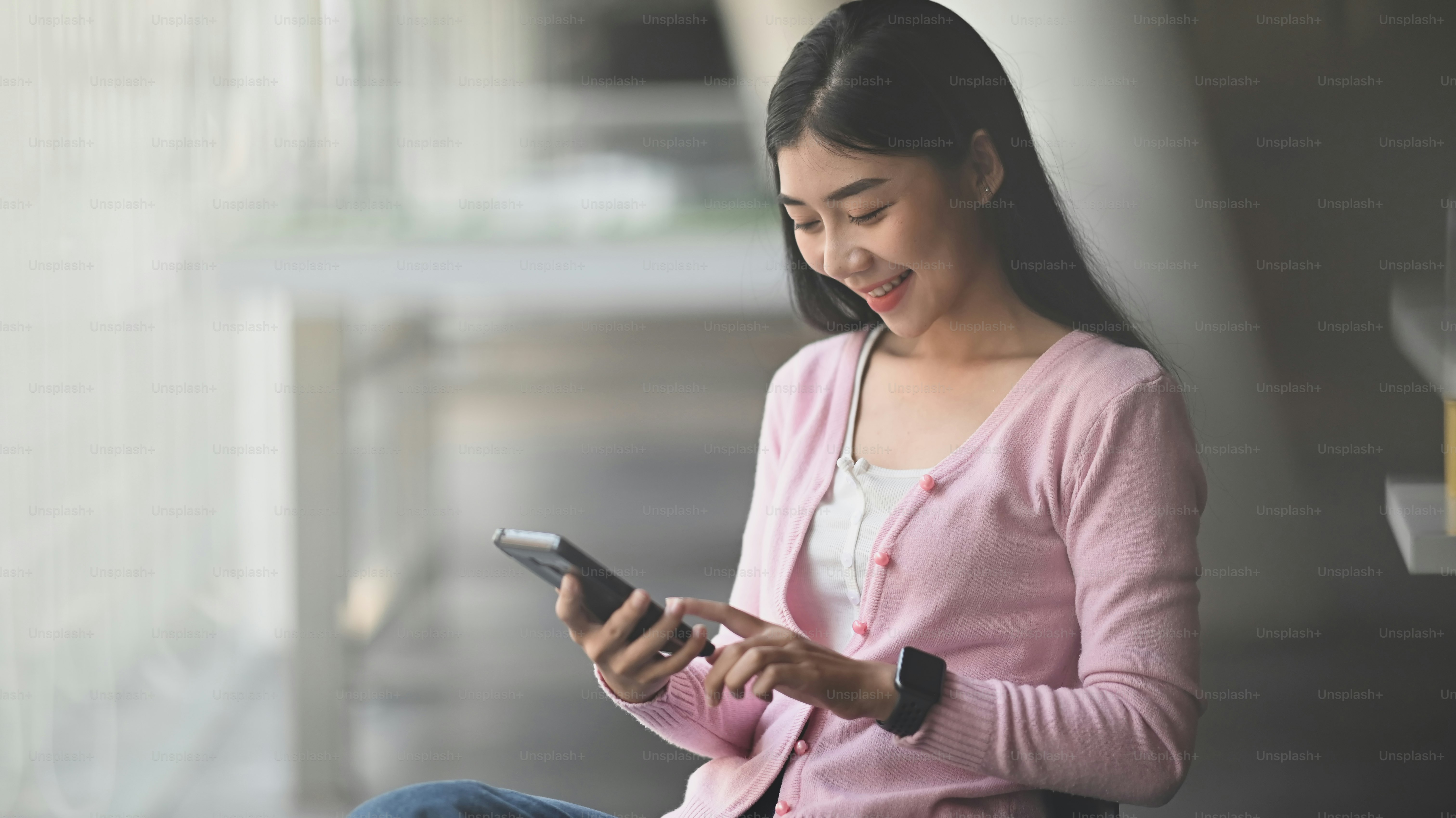 携帯電話を持って見ながら微笑む若い美しい女の子。幸せのサラリーマンのコンセプト。