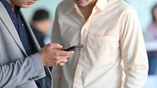 Cropped shot of business man and his colleague using phone together while talking/planning them work at the office.