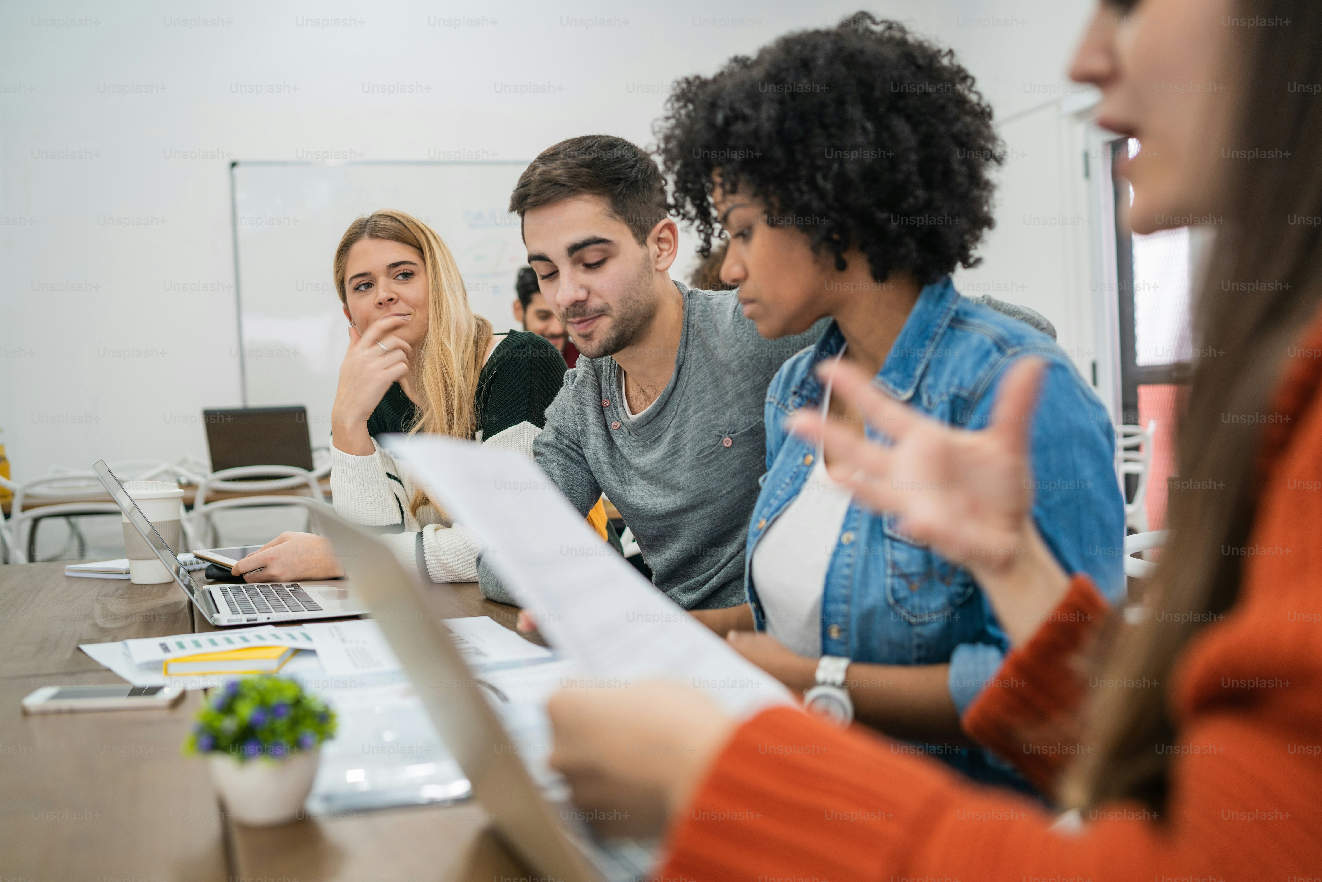 Junge kreative Designer, die an einem Projekt arbeiten und über die Entwicklung neuer Ordnungen am Arbeitsplatz diskutieren. Geschäfts- und Teamarbeitskonzept.