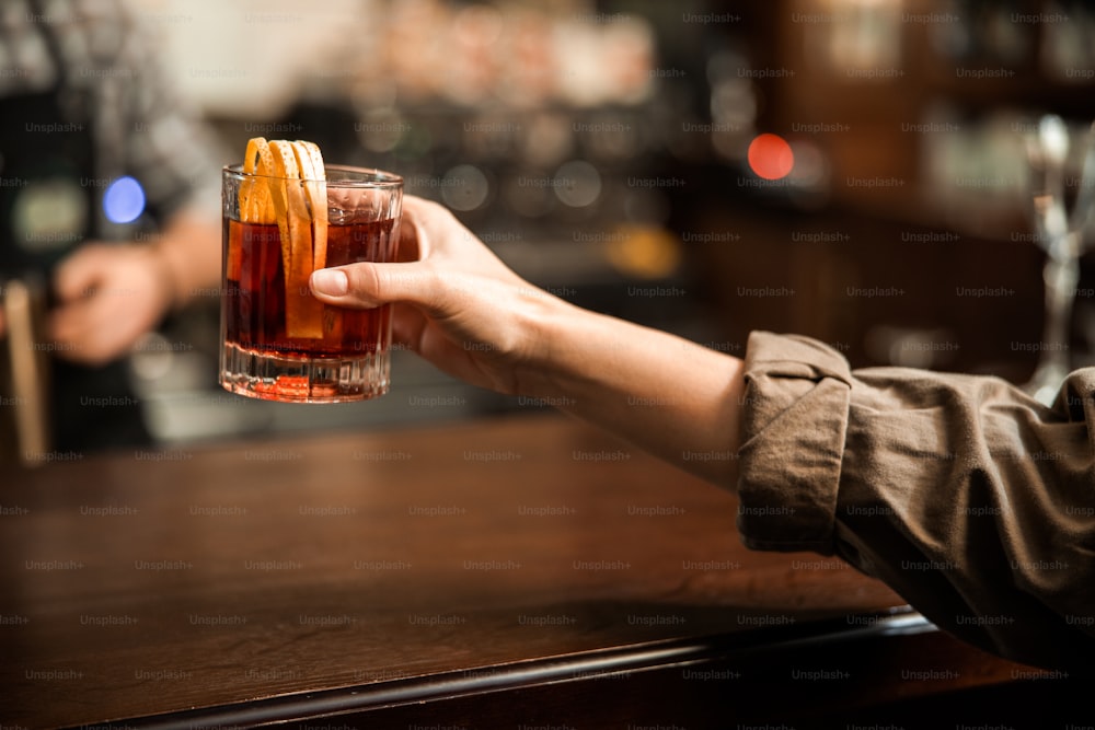 Primo piano della mano femminile con bevanda alcolica al bar - Foto stock