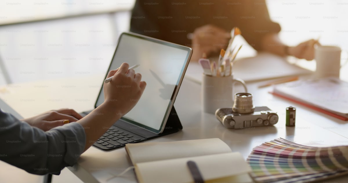 Close up view of female app developer drawing on mock up tablet while ...