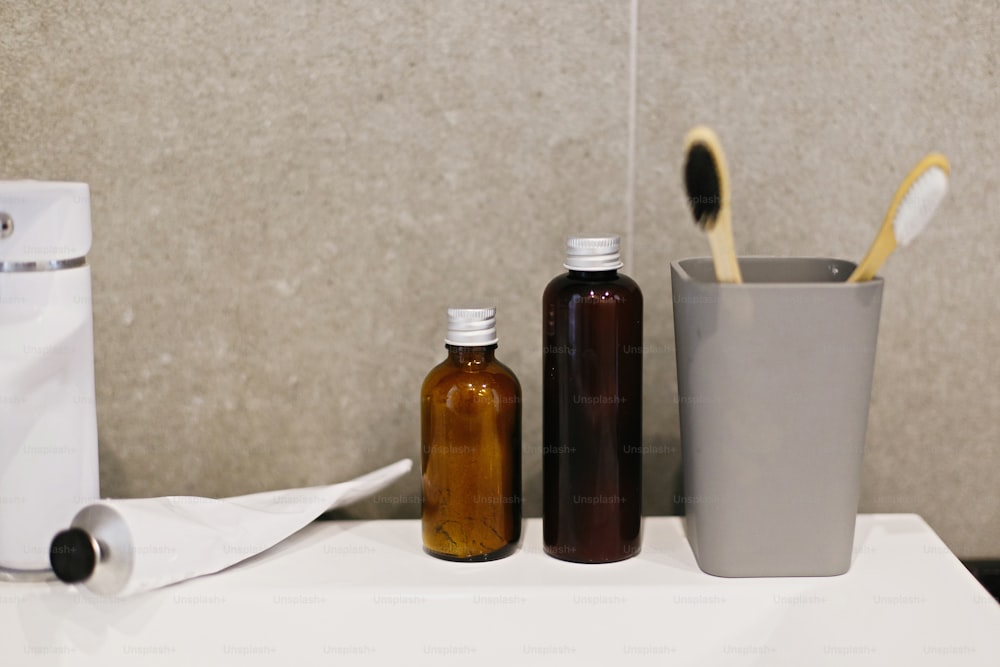 Zero waste concept. Bamboo toothbrush, ubtan for skin in glass bottle, toothpaste in metal tube, tonic on white sink in modern bathroom. Plastic free. Sustainable lifestyle