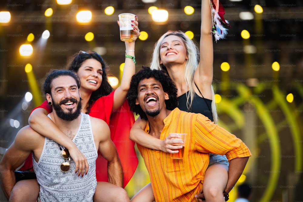 Group of happy friends having fun time at music festival