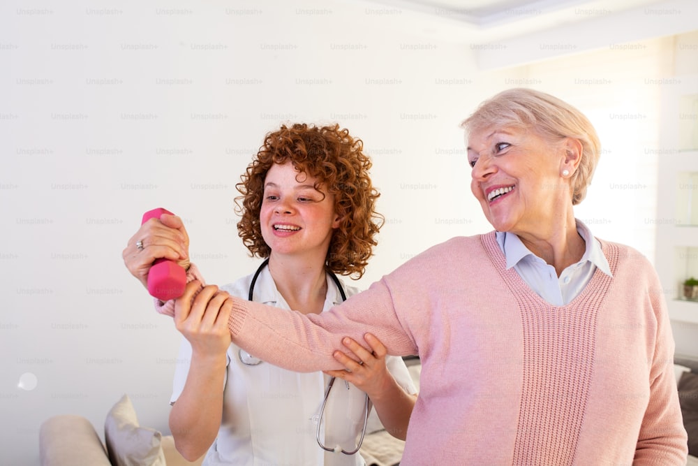 Une femme âgée après un accident vasculaire cérébral dans une maison de soins infirmiers fait de l’exercice avec un physiothérapeute professionnel. Femme âgée retrouvant une bonne santé. infirmière kinésithérapeute aidant une femme âgée en réadaptation physique