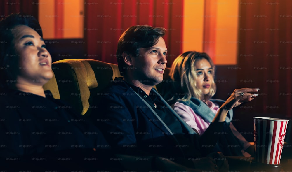 Caucasian lover and woman sitting next to them enjoying to watch movie