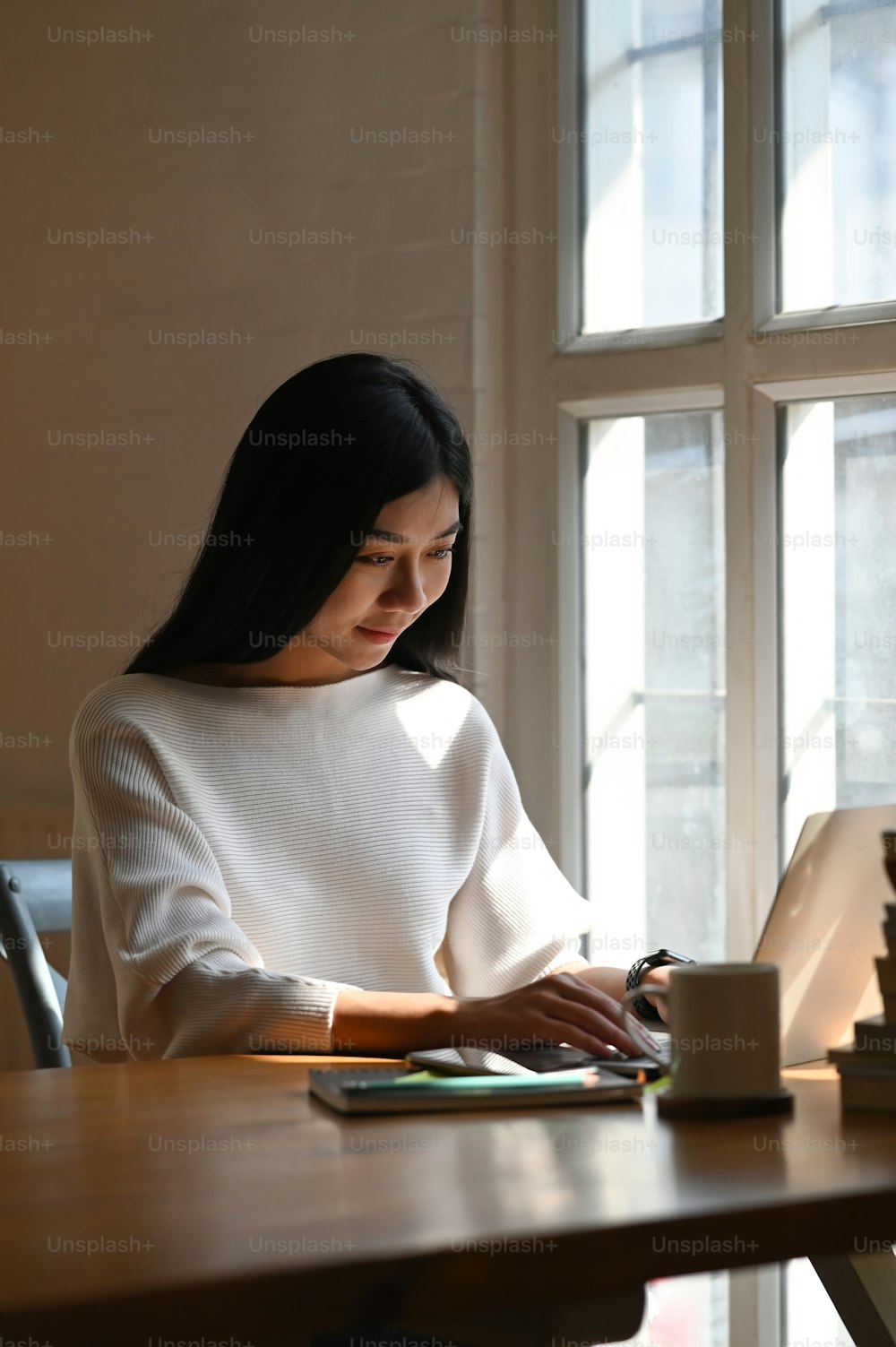 Portrait shot asian woman using her laptop computer on library table.