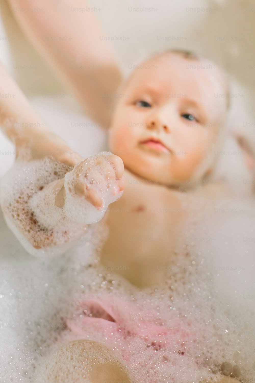 Glückliches kleines Baby ein Schwimmen im Badezimmer. Porträt eines Babys, das in einem Bad mit Schaum badet