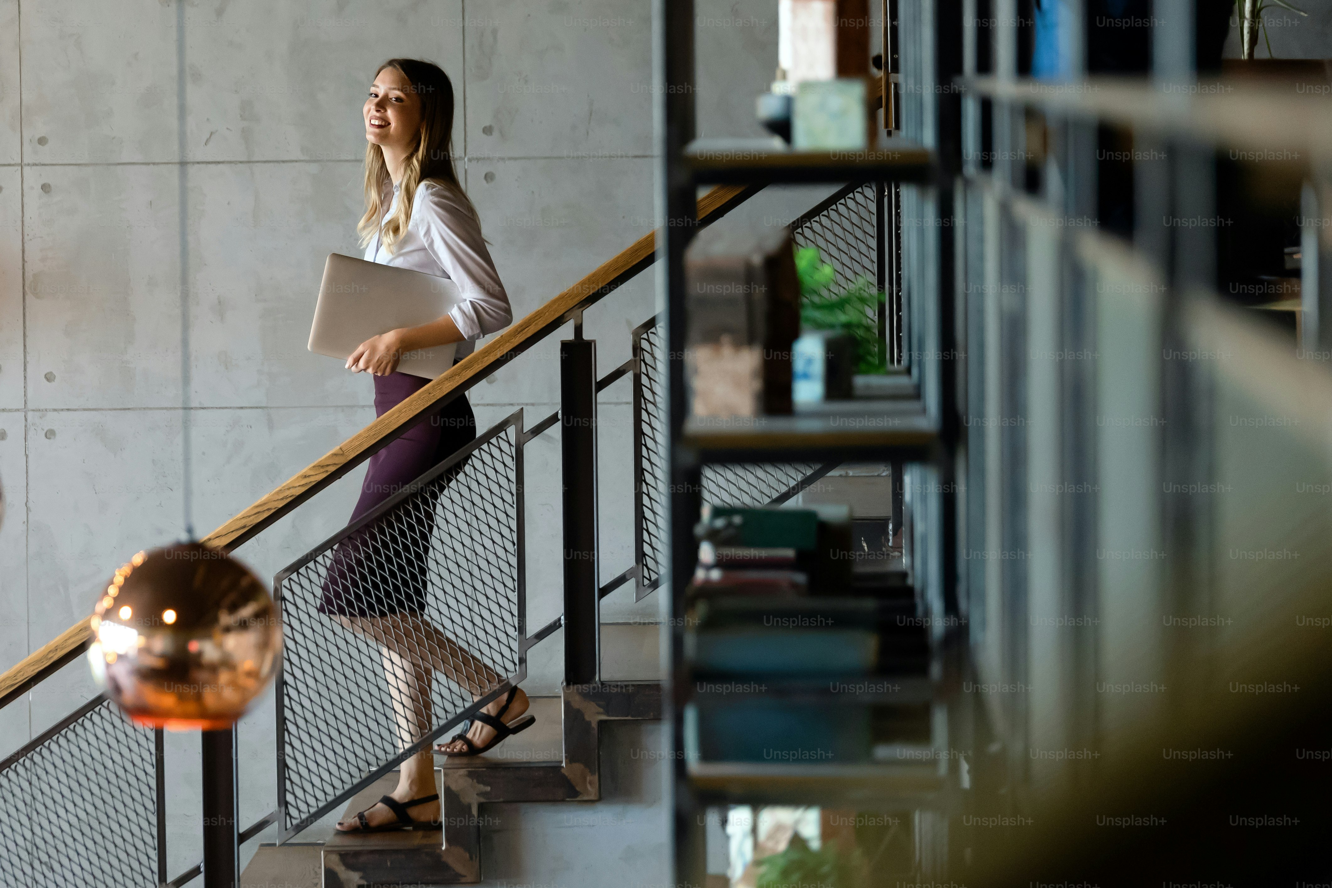 Beautiful modern young businesswoman holding laptop computer in office