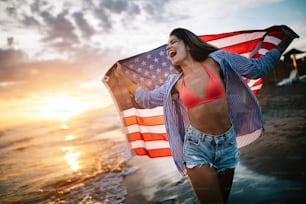 Happy woman smiling and running on beach while celebrateing independence day and enjoying freedom in USA