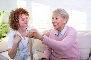 Enge positive Beziehung zwischen älterem Patienten und Pflegepersonal. Glückliche ältere Frau, die mit einer freundlichen Pflegekraft spricht. Junge hübsche Pflegerin und ältere glückliche Frau