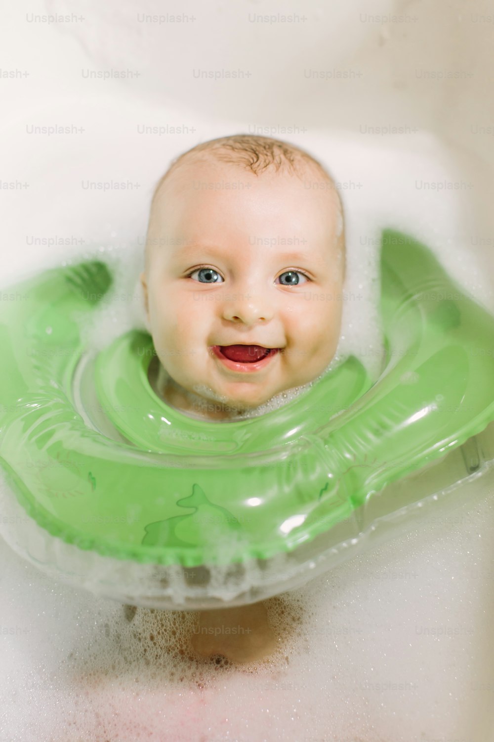 The baby is newborn, the girl is bathing in the bathroom with a inflatable circle around her neck.