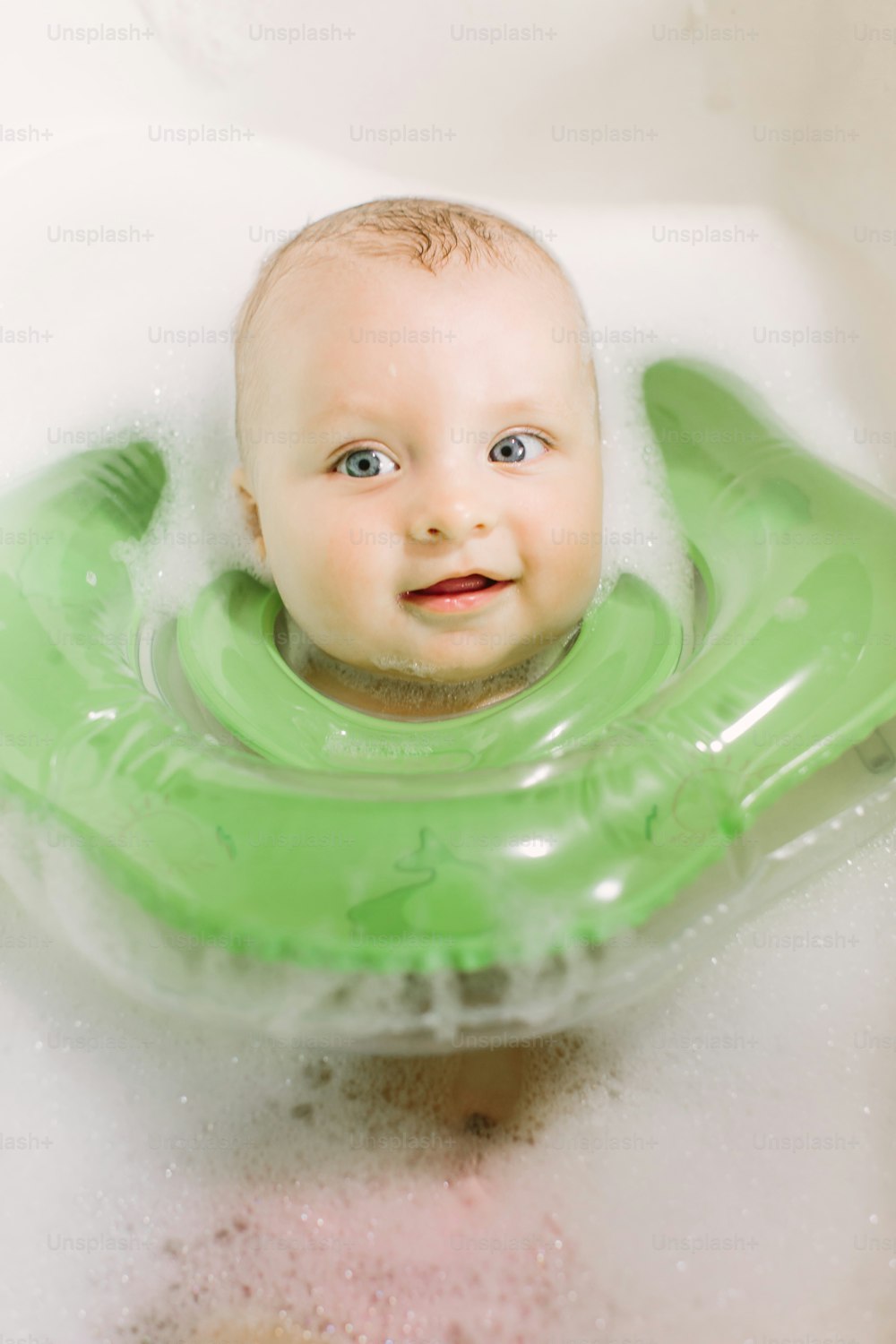 녹색 목 수영 반지와 함께 수영하는 아기