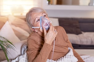 아픈 노인 여성이 흡입을하고, 약은 최고의 약입니다. 산소 마스크를 쓰고 치료를 받고 있는 아픈 노인 여성. 흡입기를 가진 노인 여성