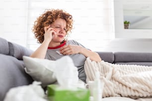 Young woman getting bad news by phone. unhappy woman talking on mobile phone looking down. Crying depressed girl holds phone sitting on sofa hopeless , breaking up, scared of threatening, mobile abuse