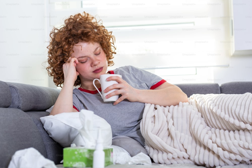 Depressed woman laying on a desk with a cup of coffee in hand, Upset depressed young woman lying on couch feeling headache migraine, sad tired drowsy teenager exhausted girl is nervous and stressed