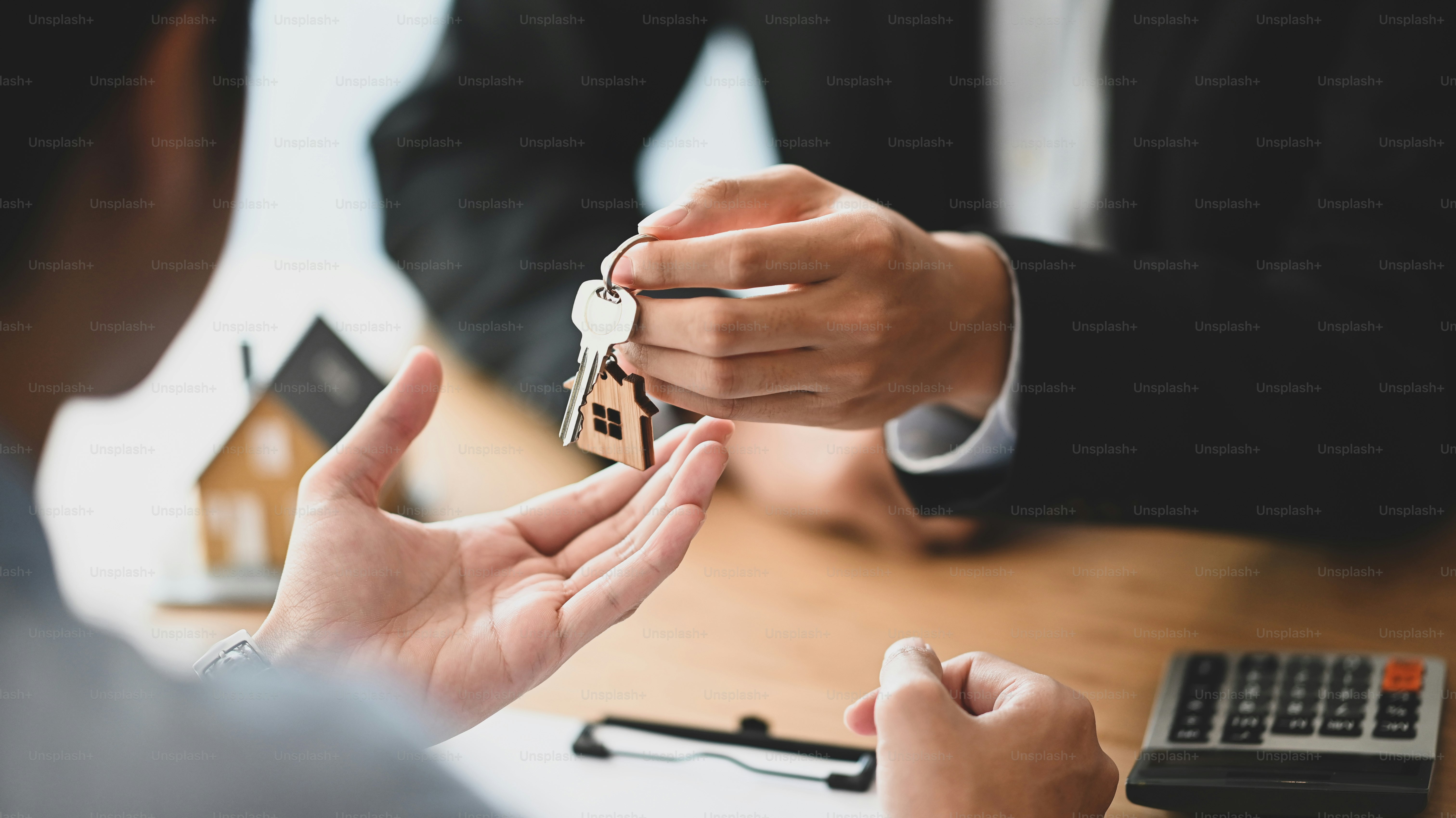 Une personne en costume qui remet les clés de maison à une autre personne à un bureau