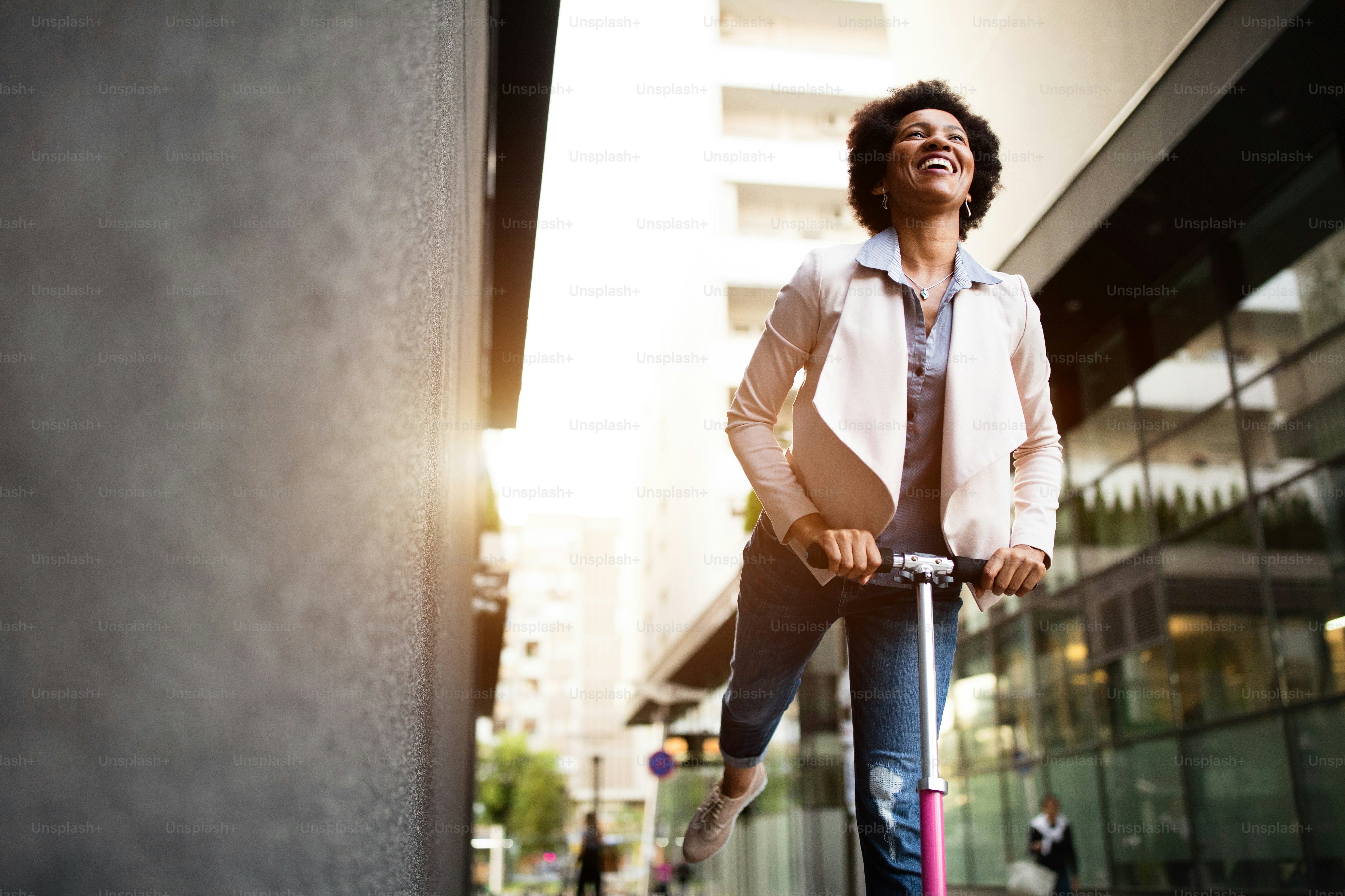 Happy beautiful woman riding an electric scooter on the street