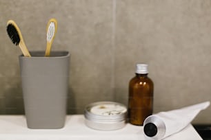 대나무 칫솔, 피부를위한 ubtan, 금속 캔의 단단한 샴푸, 현대적인 욕실의 흰색 싱크대에 금속 튜브에 치약. 폐기물 제로 개념. 플라스틱 무료. 지속 가능한 라이프 스타일