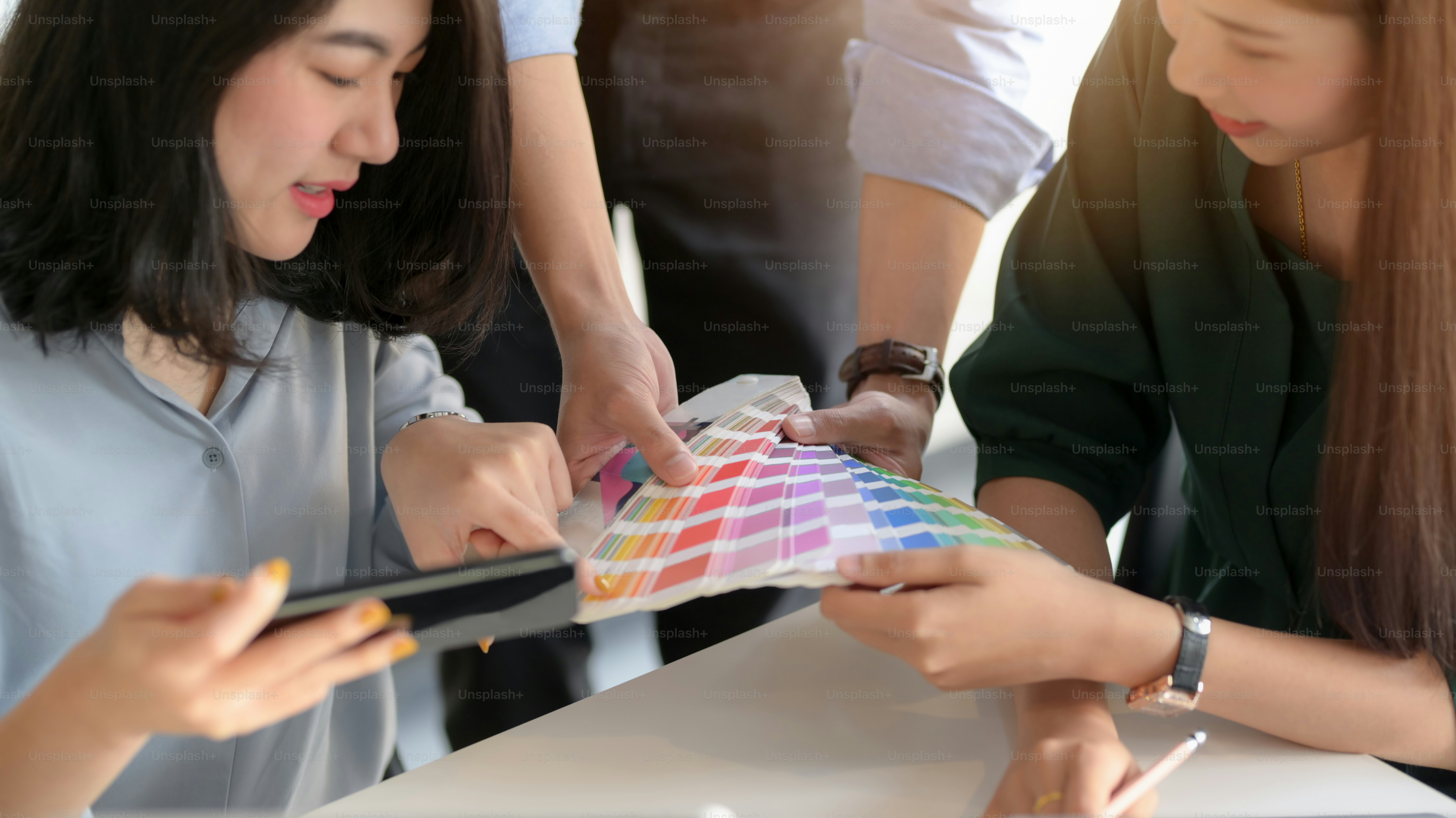 Cropped shot of professional designer team using smartphone while consulting on their project in simple co working space