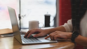 Close up female typing her laptop computer in coffee cafe.