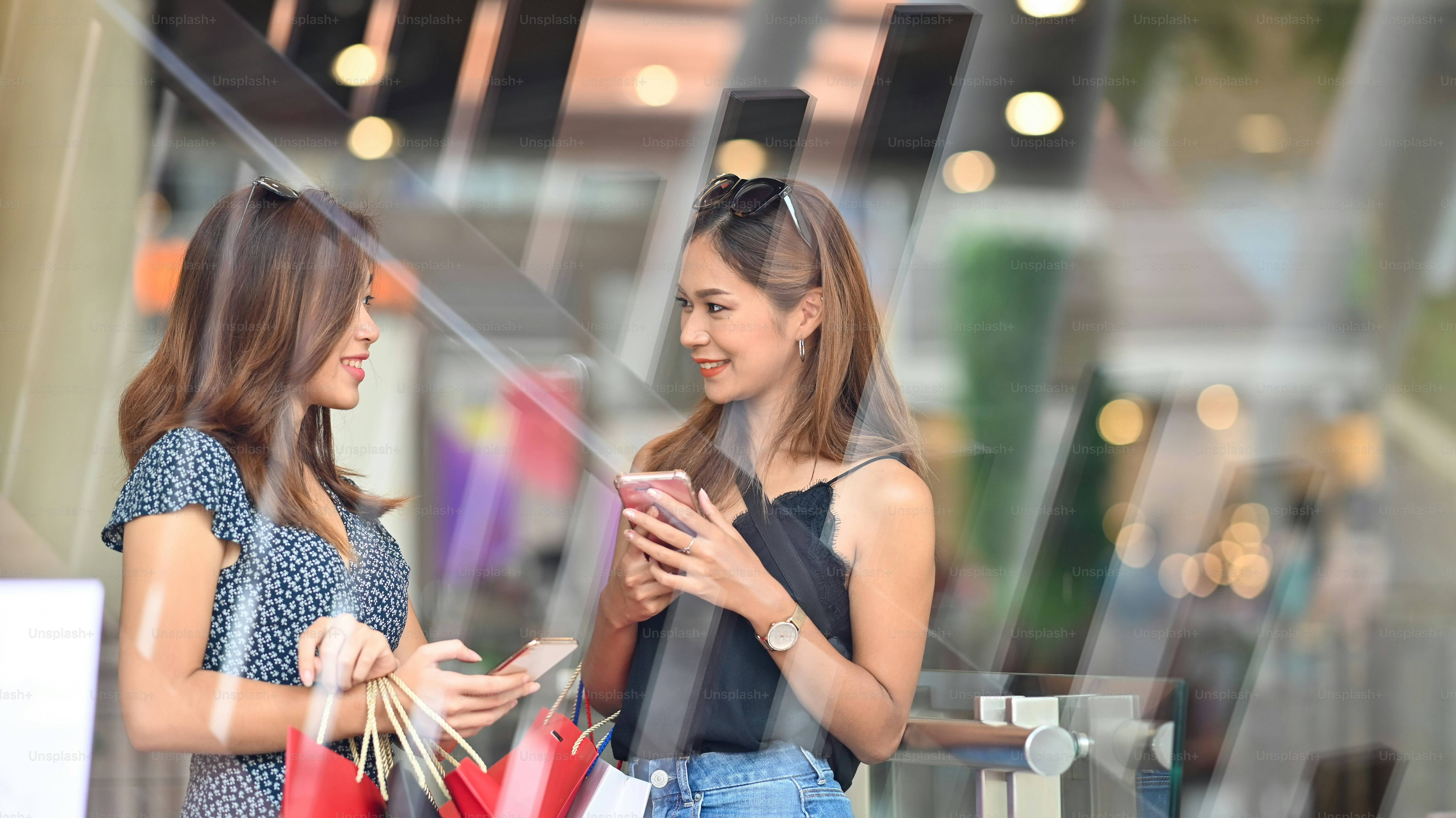 Beautiful women behind the supermarket glass wall, they talking/relaxing after finished shopping at the urban supermarket. Women relaxing/shopping with blurred background.
