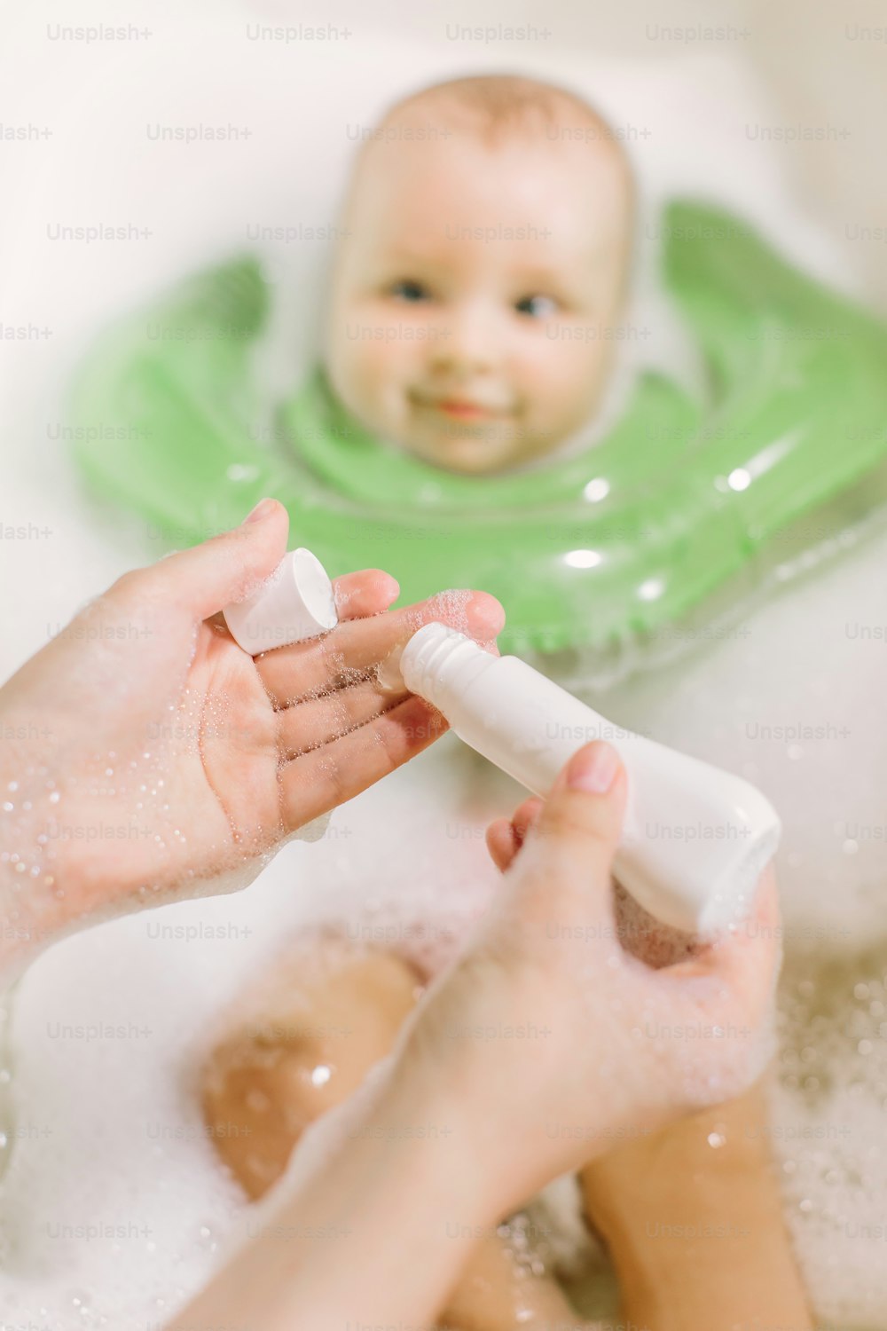 Baby swimming with green neck swim ring. mom squeezes shampoo out of the tube
