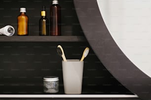 Zero-Waste-Konzept. Plastikfreie Bambuszahnbürste, Holzkohle-Zahnpasta in Glas, ubtan für die Haut, Conditioner, Deodorant, Tonic im modernen Badezimmer in schwarzen Regalen. Natürliche Grundlagen