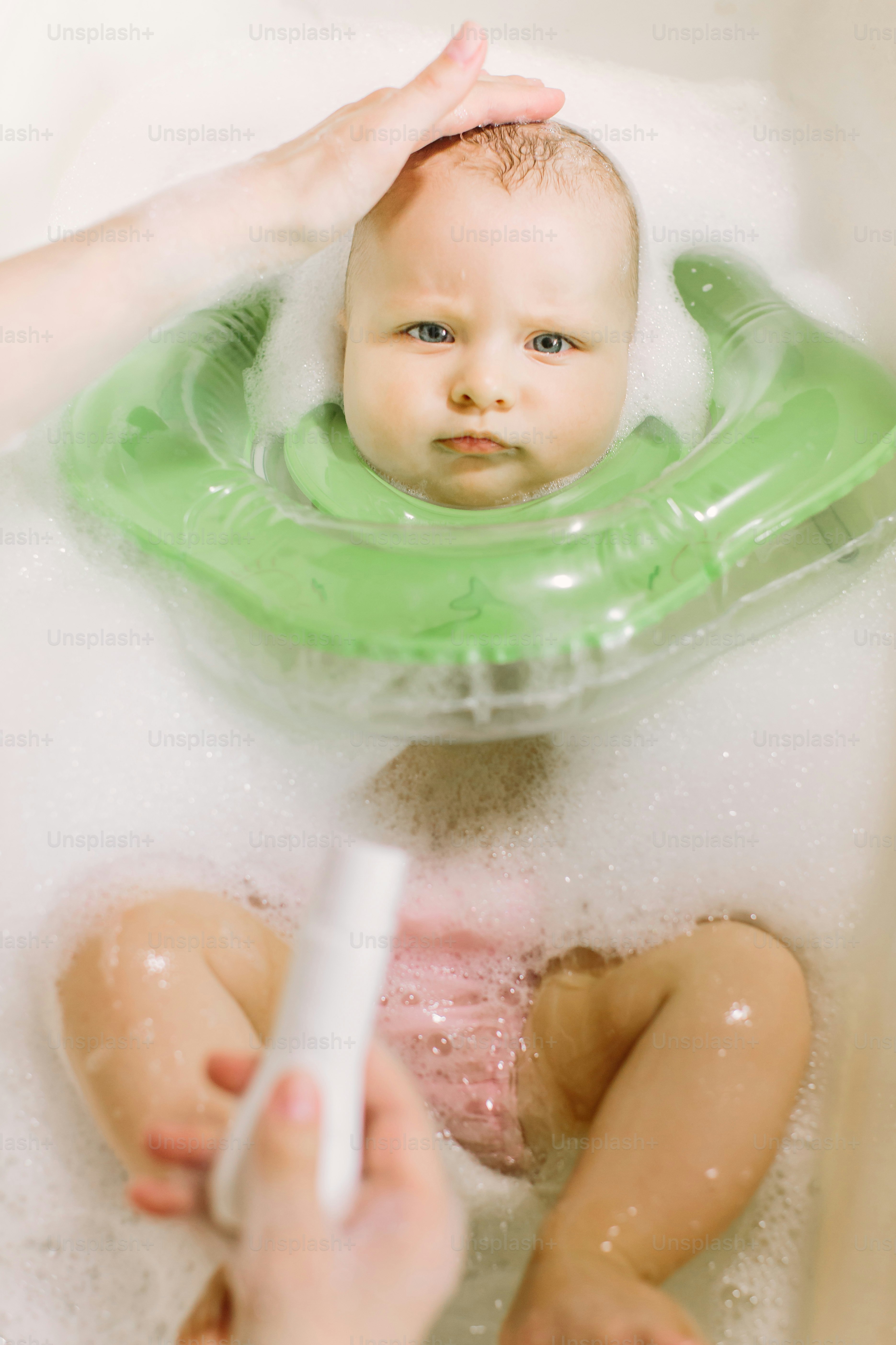 Baby swimming with green neck swim ring. mom squeezes shampoo out of