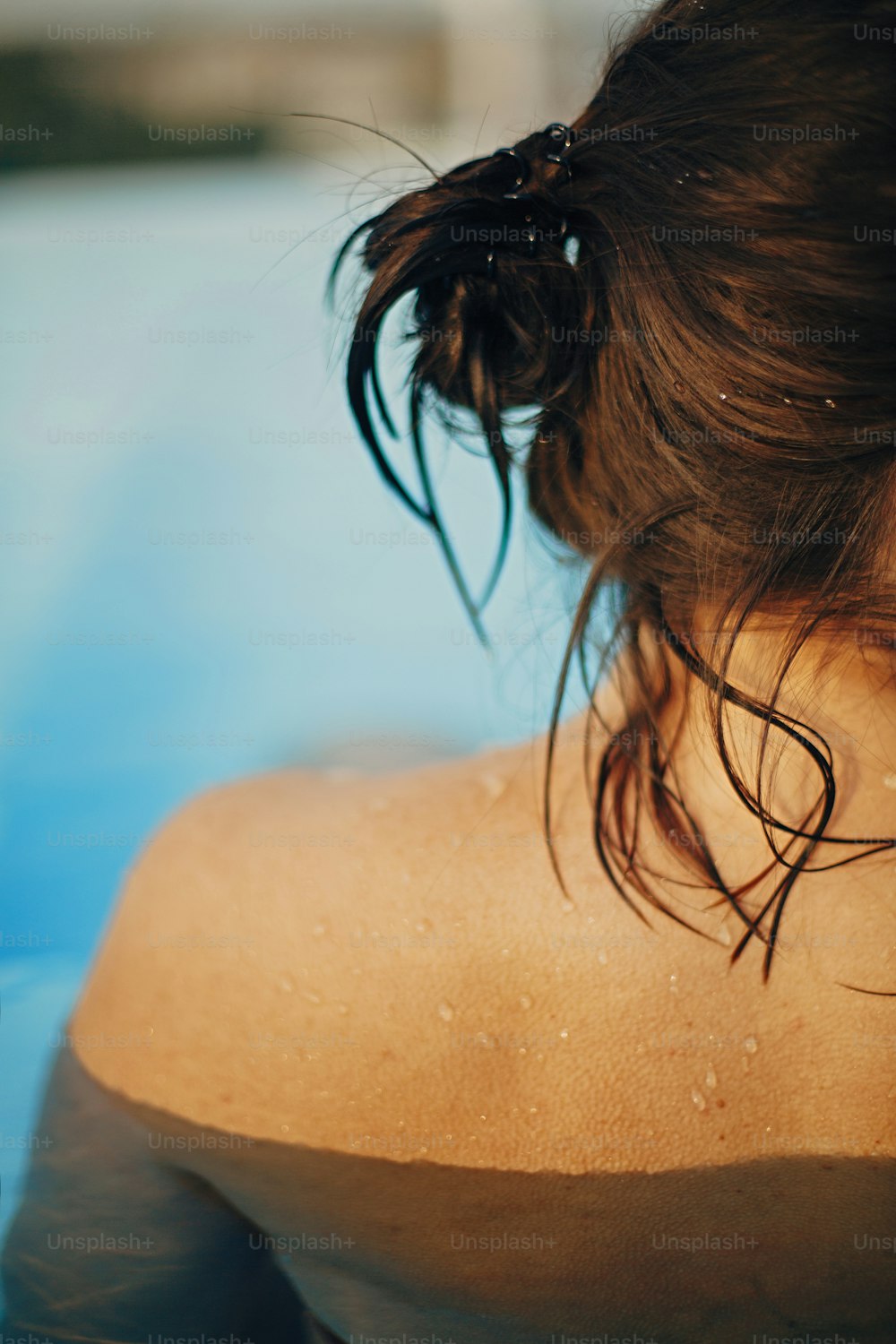 Beautiful woman back  with water drops close up, relaxing in pool. Back view of brunette girl with wet skin with goosebumps. Summer vacation. Enjoying summer holiday, swimming in pool
