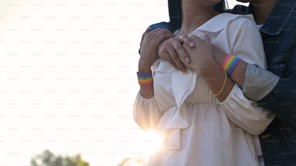 Cropped shot of young LGBT Lesbian embracing her lover from the back at the beautiful park with the sunset light as background. LGBT Happiness couple concept.