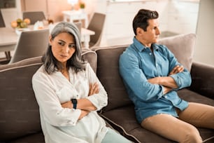 Adult couple sitting on the couch while having quarrel stock photo