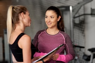 Personal trainer guding young woman at gym