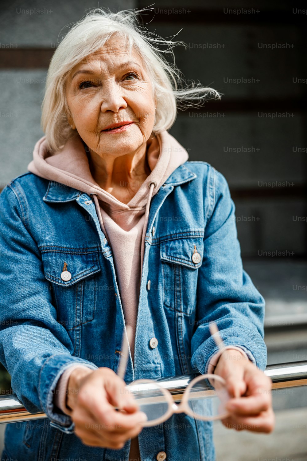 차분한 노인 여성은 야외에 서서 기대하고 있습니다.